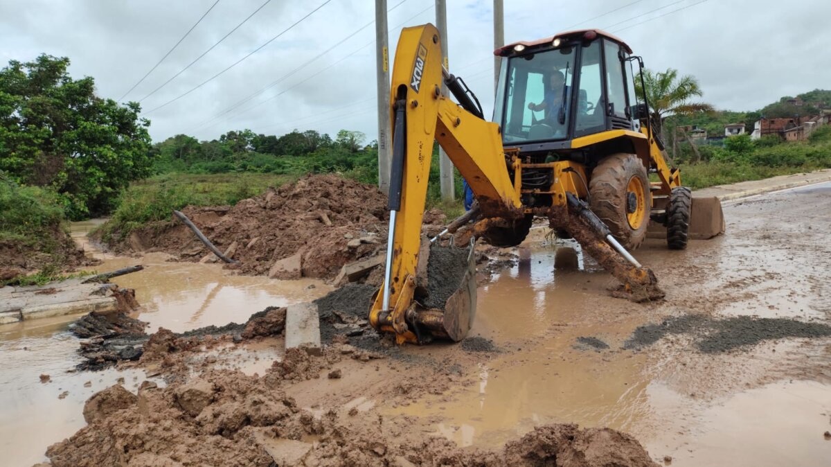 retroescavadeira rompendo asfalto para passagem do rio sergimirim