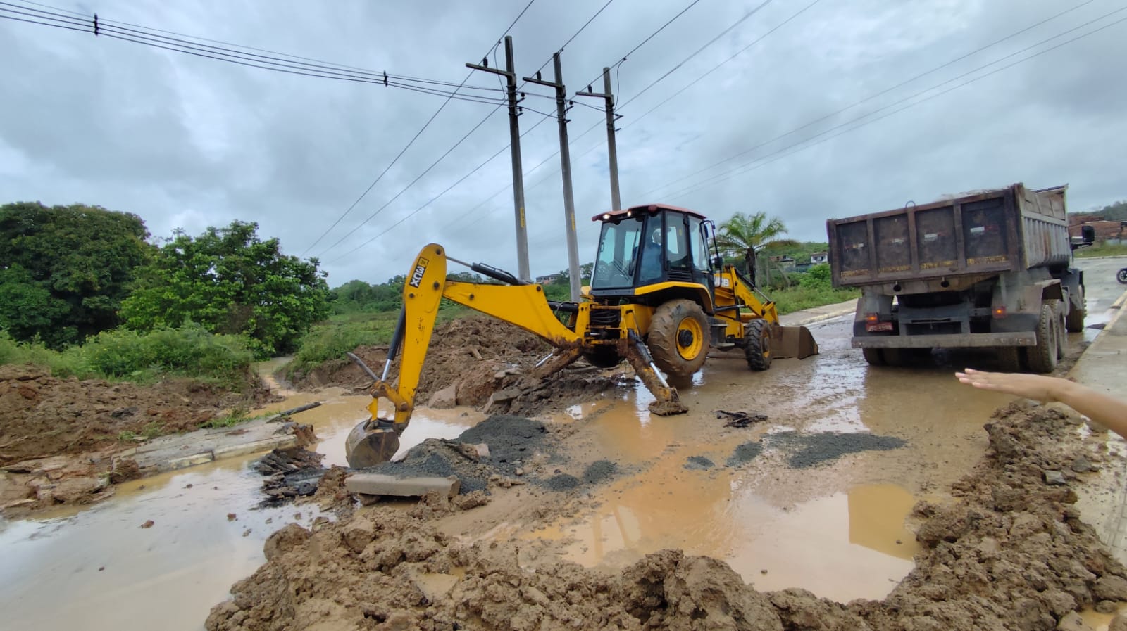 retroescavadeira rompendo asfalto para passagem do rio sergimirim