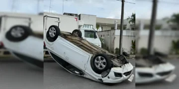 Carro de passeio de cor prata capotado com as quatro rodas para cima no meio de uma rua residencial asfáltica em Santo Antônio de Jesus