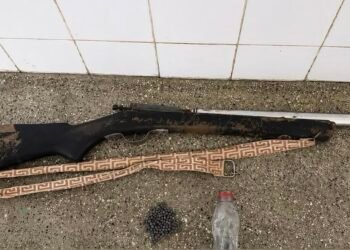 Uma espingarda de caça de madeira e metal deitada sobre uma mesa