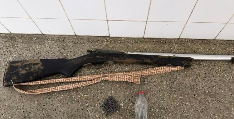 Uma espingarda de caça de madeira e metal deitada sobre uma mesa