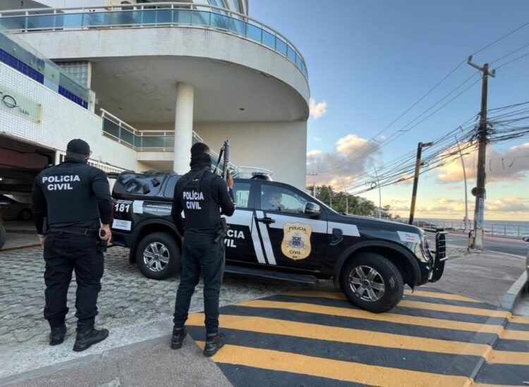 Carro da Polícia Civil com dois policiais parados em frente a uma residência