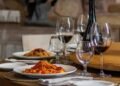 Praia do Forte recebe edição do Clube do Vinho reunindo chefs internacionais, alta enologia e debates geopolíticos no Polomar Bahia 3 clube do vinho - imagem de mesa posta com garrafa de vinho, taça e jantar servido