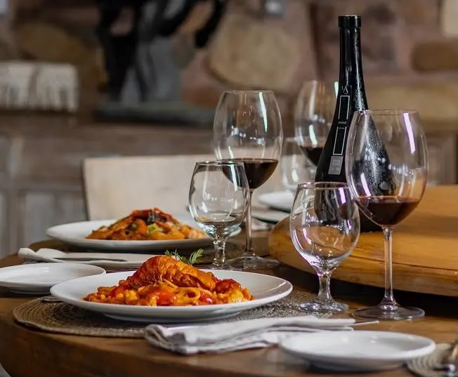 clube do vinho - imagem de mesa posta com garrafa de vinho, taça e jantar servido