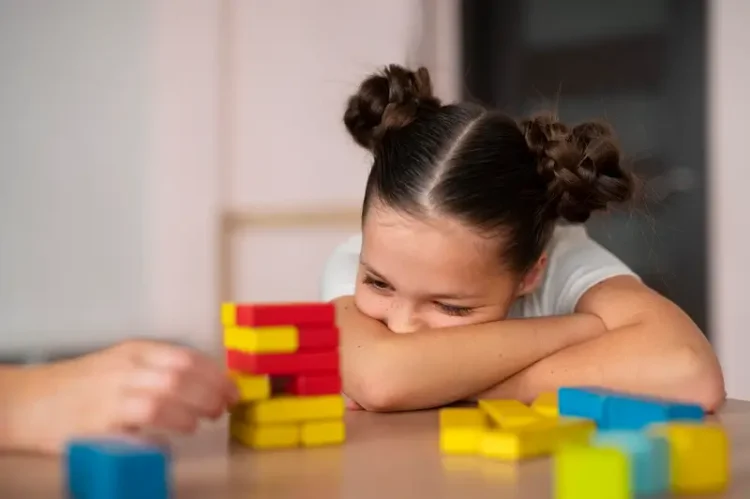 Ronco infantil pode ser confundido com TDAH: Especialista alerta para distúrbios do sono na infância 1 criança debruçada sobre os braços observando brinquedos educativos sobre a mesa