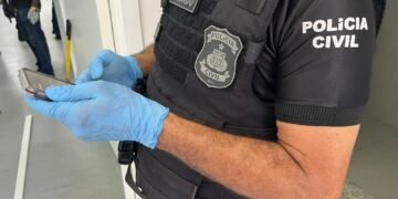 policial civil segurando um celular apreendido