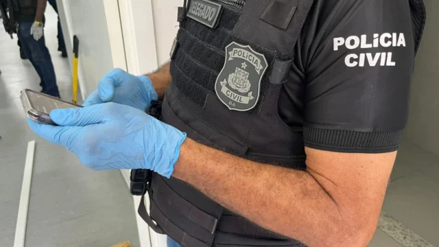 policial civil segurando um celular apreendido