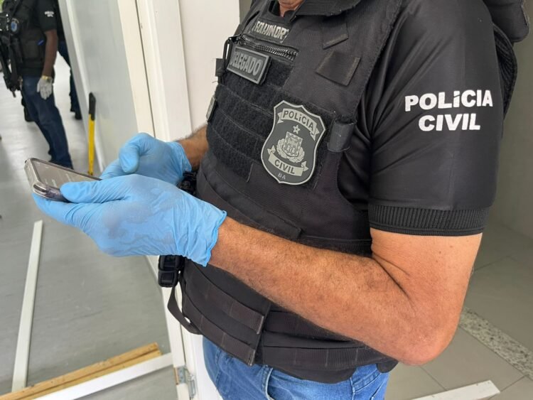 policial civil segurando um celular apreendido