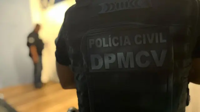 Imagem de um policial, de costas, mostrando o colete escrito: Polícia Civil - DPMCV