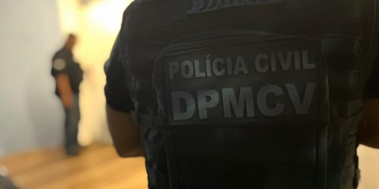 Imagem de um policial, de costas, mostrando o colete escrito: Polícia Civil - DPMCV