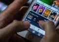 foto mostra uma pessoa segurando celular mostrando o app de uma bet aberto no aparelho