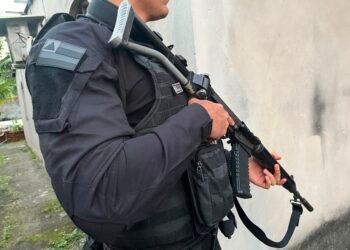 policial segurando arma enquanto trabalha