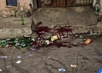 rua cheia de garrafas de cervejas no chão com manchas de sangue após tiroteio em festa paredão em Santo Amaro