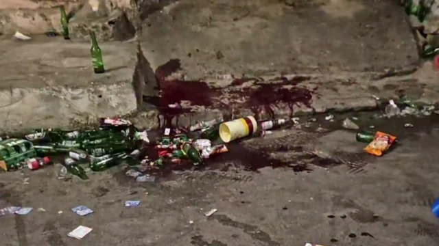 rua cheia de garrafas de cervejas no chão com manchas de sangue após tiroteio em festa paredão em Santo Amaro