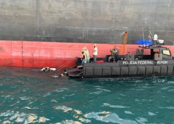 barco da Polícia Federal com policiais interceptando navio de cargas
